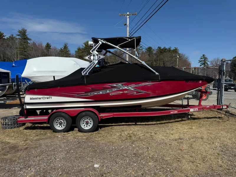 Slide: The Image of 2010 MasterCraft X-25 boat on trailer, red and black design, parked outdoors. - 9