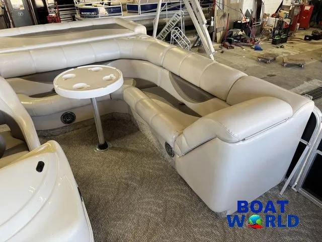Slide: The Image of 2008 South Bay 20' Cruise Pontoon with beige seating and table in a showroom. - 14