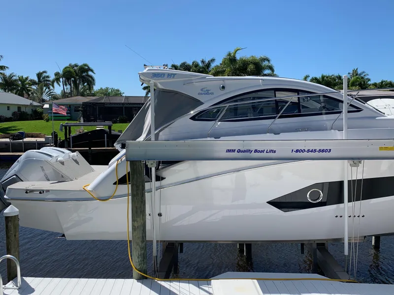 The Image of 2022 Evolve 360HT boat on lift, docked near waterfront homes. - 0