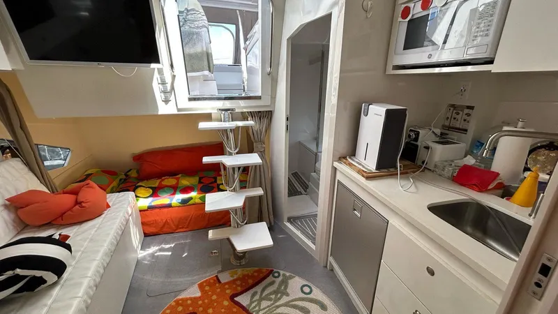 Slide: The Image of Compact interior of 2022 Evolve 360HT camper with modern kitchen, cozy seating, and colorful bedding. - 46