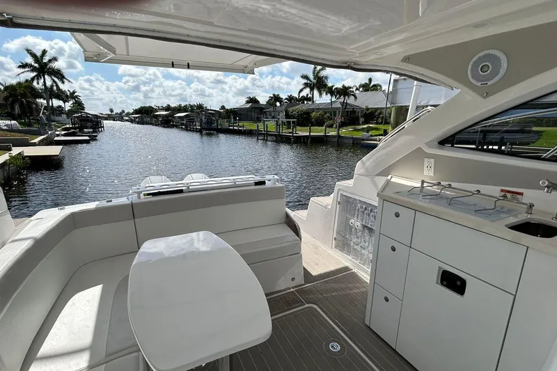 Slide: The Image of Luxury Evolve 360HT yacht interior with waterfront view, featuring sleek seating and kitchenette. - 57