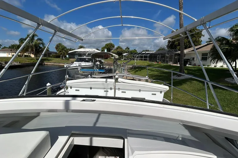 Slide: The Image of Boat docked in a canal, surrounded by palm trees and houses, under a clear blue sky. - 68