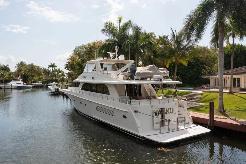 Slide: The Image of 2004 Cheoy Lee 84 Bravo Flybridge yacht docked by palm trees in a serene canal. - 2