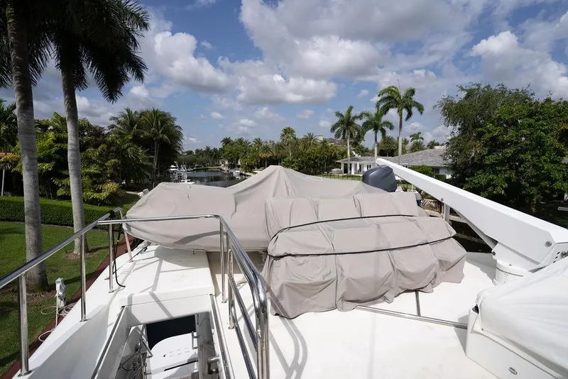 Slide: The Image of 2004 Cheoy Lee 84 Bravo Flybridge yacht deck with covered equipment, surrounded by palm trees. - 42
