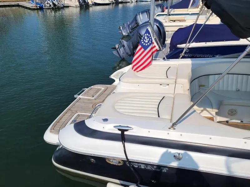 Slide: The Image of 2003 Cobalt 263 boat docked, featuring a rear seating area and American flag. - 3
