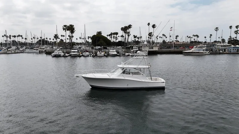 Slide: The Image of 2007 Luhrs 41 Express boat in a marina with palm trees and cloudy sky. - 11