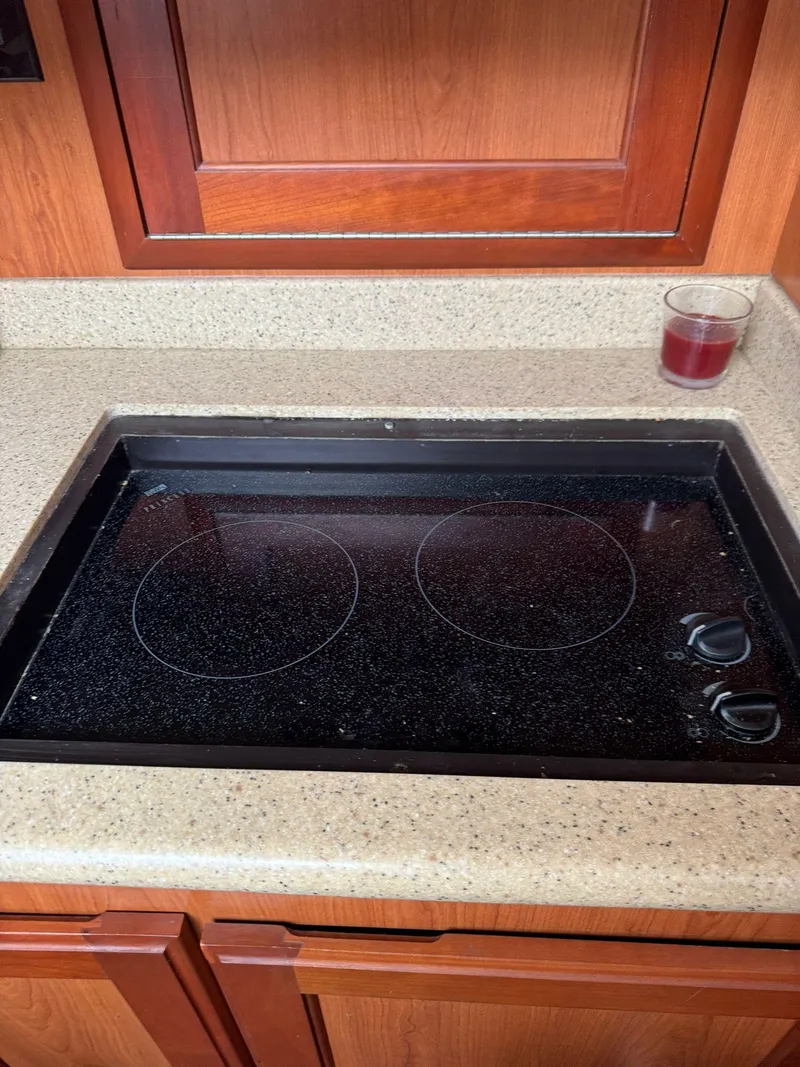 Slide: The Image of 2007 Luhrs 41 Express kitchen with electric stovetop and wooden cabinetry. - 38