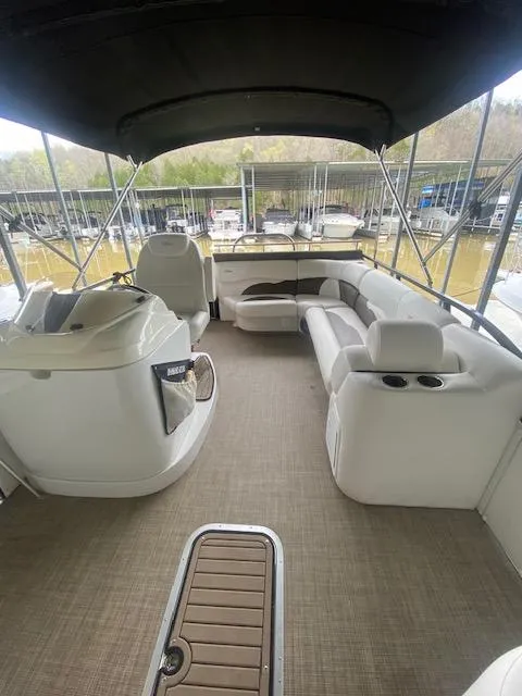 Slide: The Image of 2018 JC TriToon boat interior with seating, helm, and canopy in a marina setting. - 10