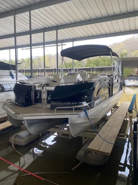 Slide: The Image of 2018 JC TriToon boat docked under a covered marina, featuring sleek design and spacious seating. - 14