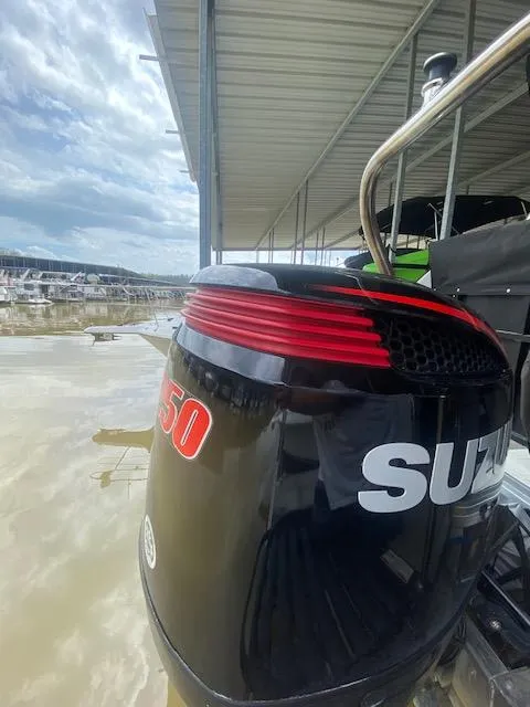 Slide: The Image of 2018 JC TriToon with Suzuki outboard motor at a marina dock. - 2
