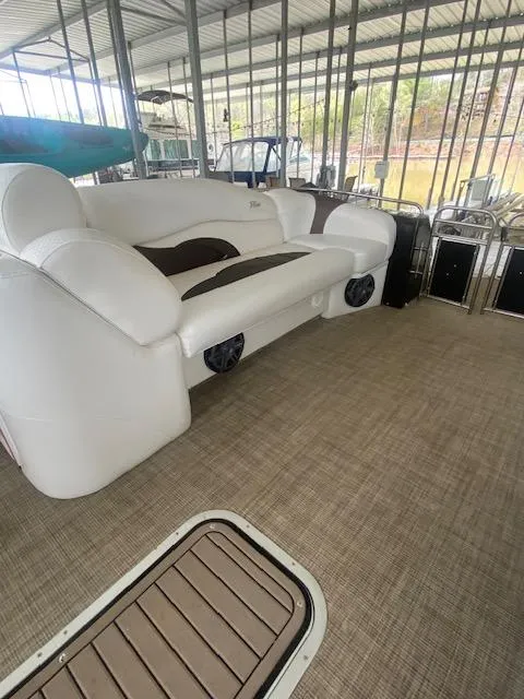 Slide: The Image of 2018 JC TriToon boat interior with white seating and spacious deck under a covered dock. - 4