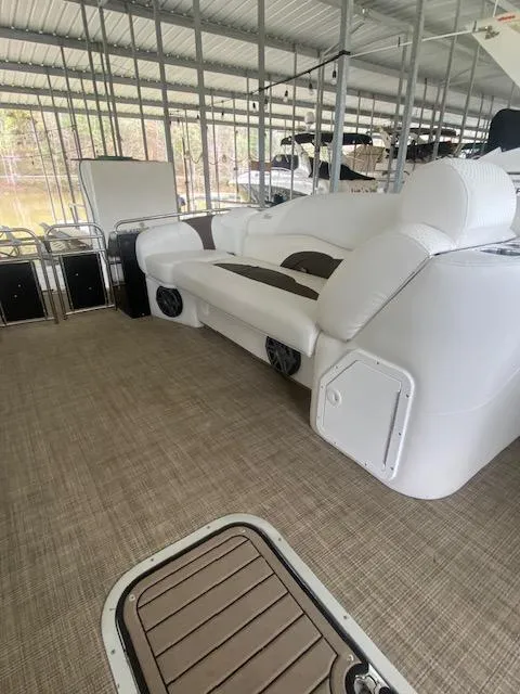 Slide: The Image of 2018 JC TriToon boat interior with white seating and spacious deck under a covered dock. - 5