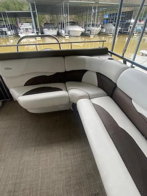Slide: The Image of 2018 JC TriToon boat interior with cushioned seating, docked near other boats. - 6