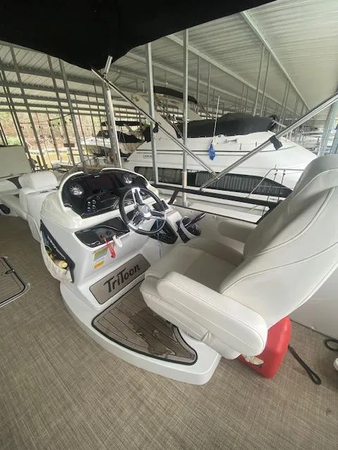 Slide: The Image of 2018 JC TriToon boat interior with steering wheel and captain's chair in marina. - 8