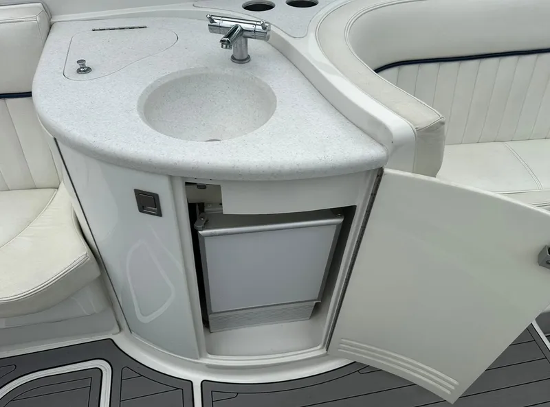 Slide: The Image of 2005 Cobalt 360 boat interior with sink, open cabinet, and seating area. - 12