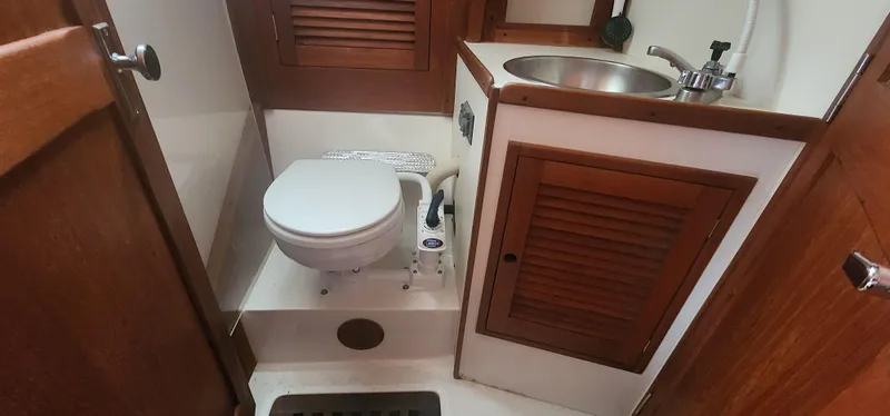 Slide: The Image of Compact bathroom in 1982 Tartan 37 sailboat with toilet, sink, and wooden cabinetry. - 21