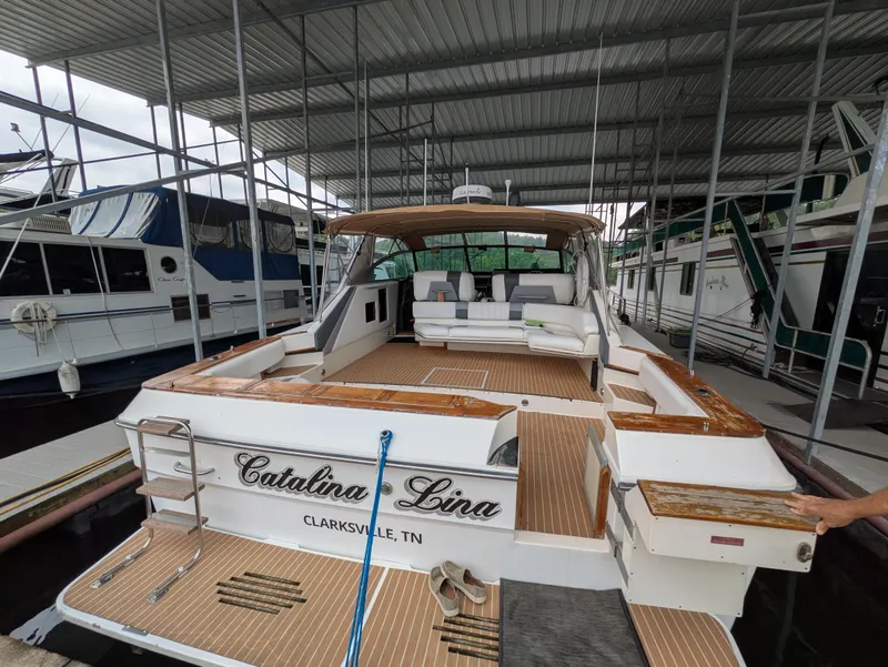 Slide: The Image of 1988 Sea Ray 460 Express Cruiser docked, featuring spacious deck and seating area. - 10