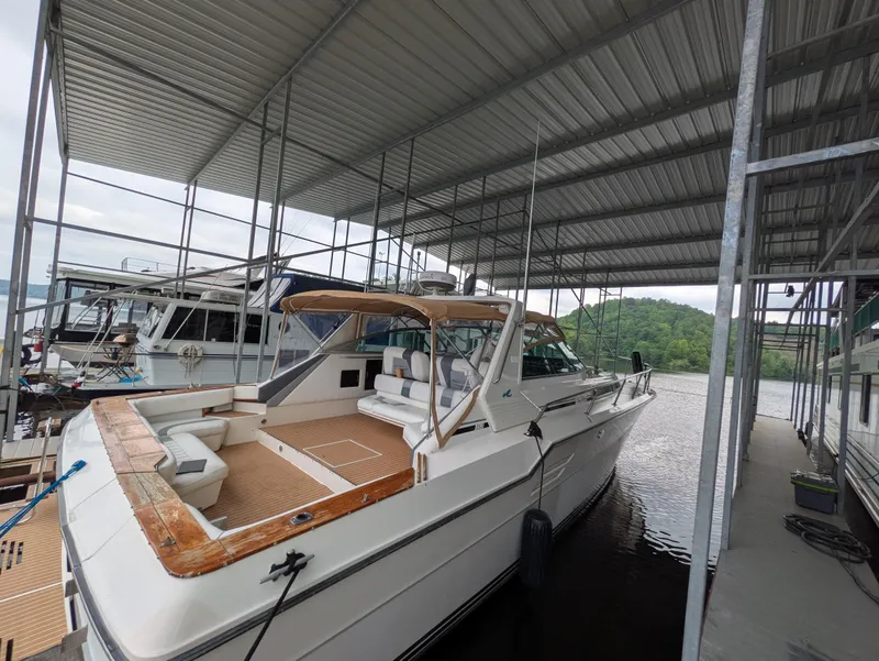 Slide: The Image of 1988 Sea Ray 460 Express Cruiser docked under a covered marina. - 14