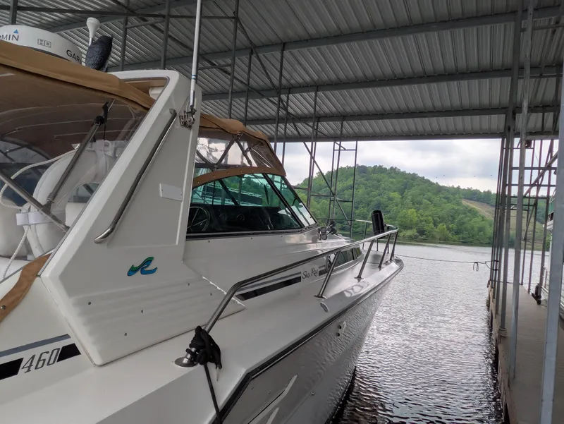 Slide: The Image of 1988 Sea Ray 460 Express Cruiser docked under a metal canopy by a scenic lake. - 17