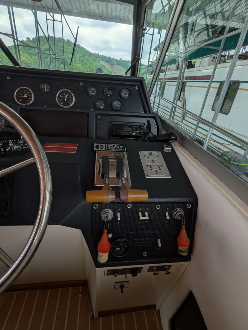 Slide: The Image of 1988 Sea Ray 460 Express Cruiser helm with gauges and controls, docked near lush greenery. - 26