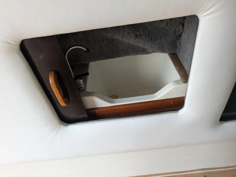 Slide: The Image of 1988 Sea Ray 460 Express Cruiser interior storage compartment with wooden handle and carpeted lining. - 38