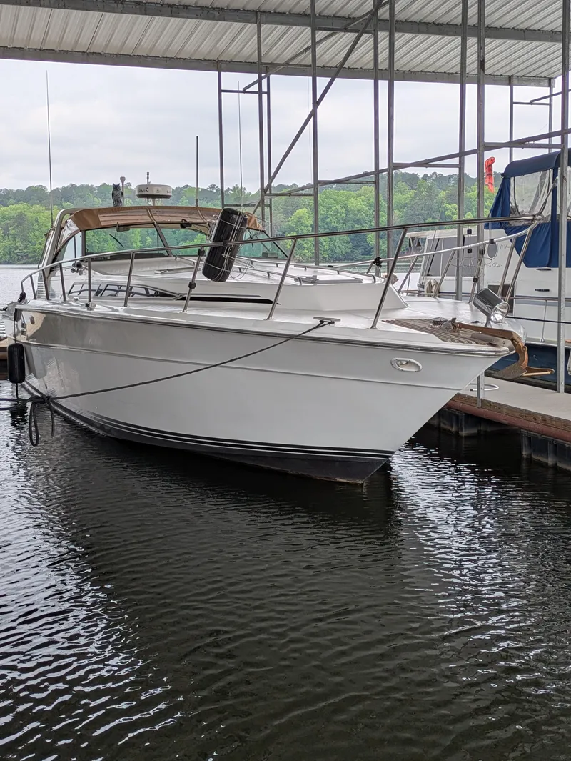 Slide: The Image of 1988 Sea Ray 460 Express Cruiser docked in a marina, surrounded by calm water. - 4