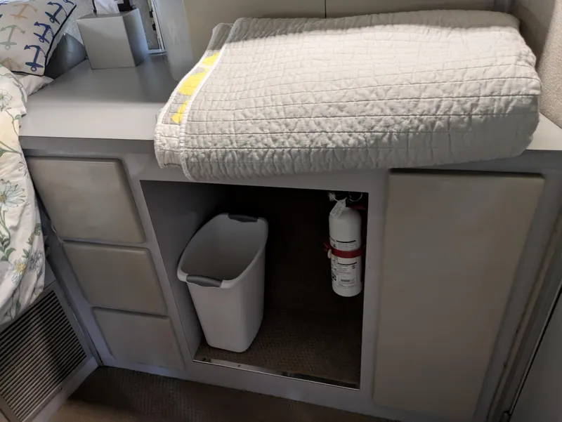 Slide: The Image of 1988 Sea Ray 460 Express Cruiser interior with storage, fire extinguisher, and folded quilt. - 43