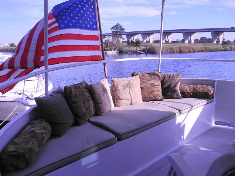 Slide: The Image of Cozy seating on 1997 Florida Bay Coasters 35 boat with American flag, near a bridge. - 8