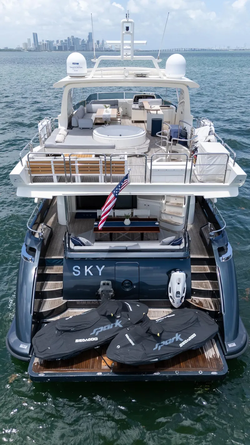 Slide: The Image of 2013 Azimut 84 Flybridge Motor Yacht on water, rear view with jet skis and city skyline. - 6