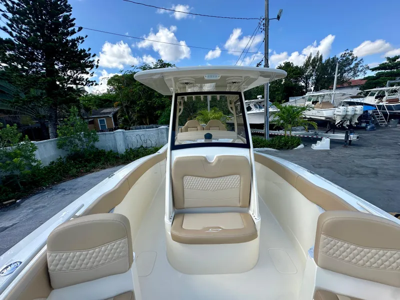 Slide: The Image of 2025 Scout 277 LXF boat with beige seating, docked outdoors under a blue sky. - 10