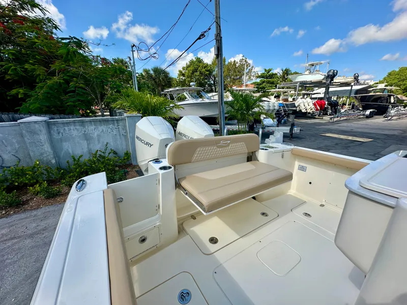 Slide: The Image of 2025 Scout 277 LXF boat with Mercury engines, docked outdoors under a clear blue sky. - 14