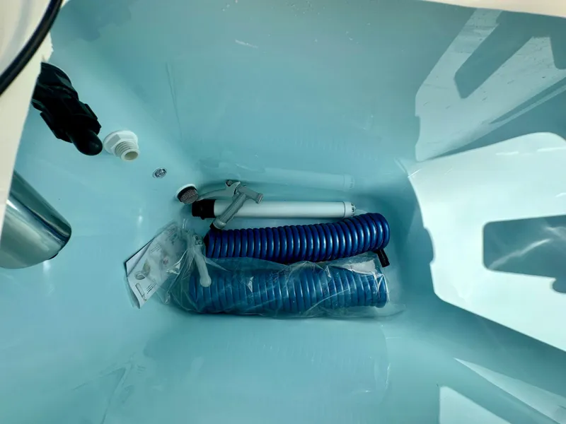 Slide: The Image of Storage compartment of 2025 Scout 277 LXF boat with coiled blue hose and accessories. - 17