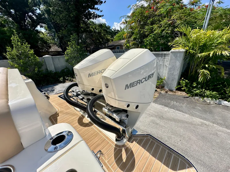 Slide: The Image of 2025 Scout 277 LXF boat with dual Mercury outboard engines, docked outdoors. - 18