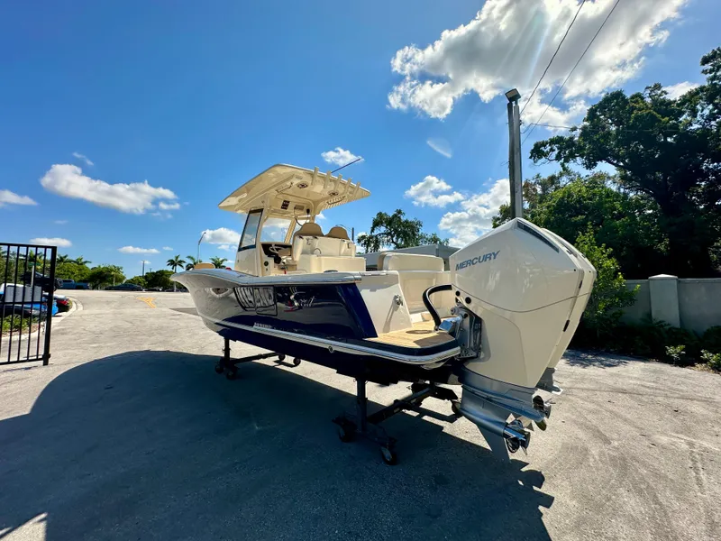 Slide: The Image of 2025 Scout 277 LXF boat with Mercury engine under clear blue sky. - 19