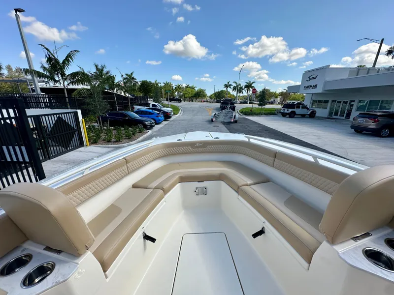 Slide: The Image of 2025 Scout 277 LXF boat interior with beige seating, parked near dealership under blue sky. - 7