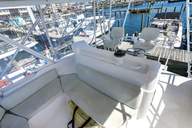 Slide: The Image of 2005 Bertram 450 Convertible yacht interior with seating, overlooking marina and boats. - 15