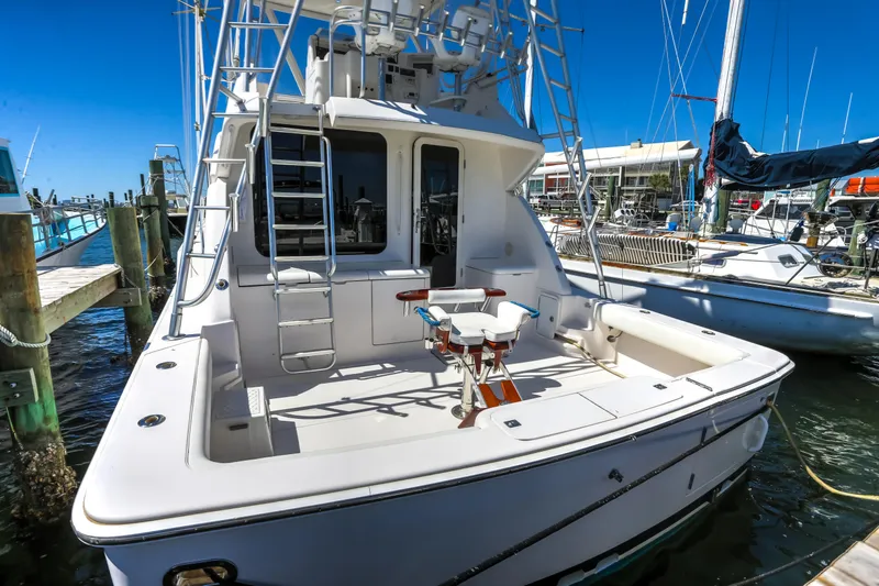 Slide: The Image of 2005 Bertram 450 Convertible yacht docked at marina, featuring spacious deck and fishing chair. - 30