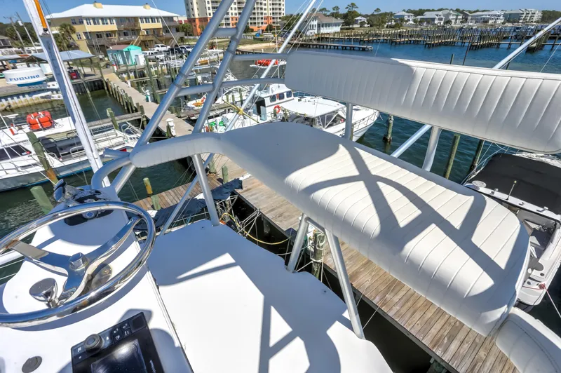 Slide: The Image of Bertram 450 Convertible 2005 yacht helm with white seating, docked at marina. - 49