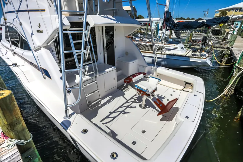 Slide: The Image of 2005 Bertram 450 Convertible yacht docked, featuring spacious deck and fishing chair. - 5