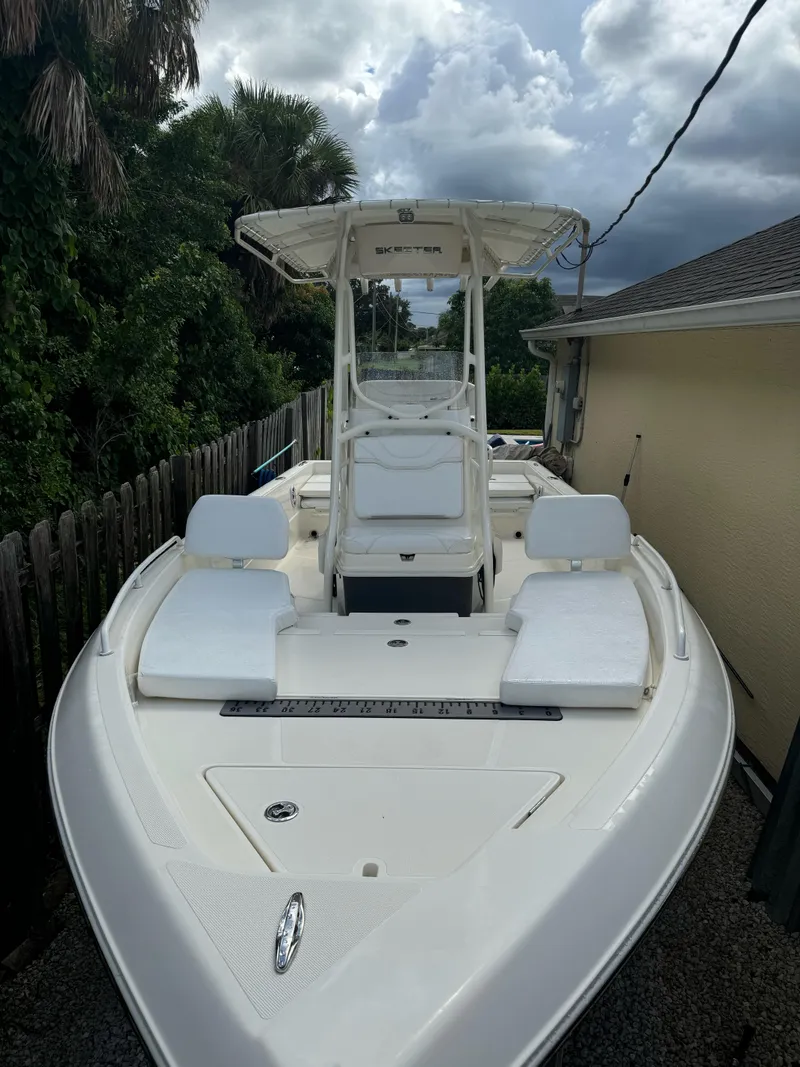 Slide: The Image of 2022 Skeeter SX2250 boat with T-top, white seating, and sleek design, parked outdoors. - 3