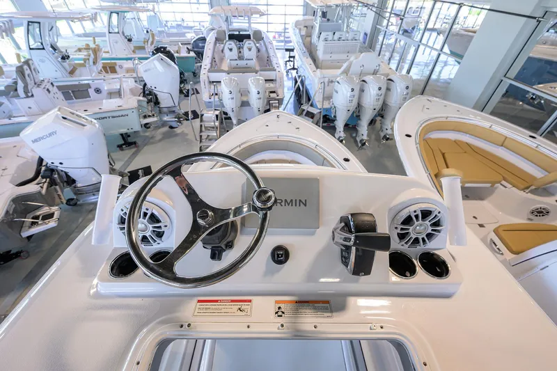 Slide: The Image of 2024 Sportsman Open 252 Center Console boat interior with steering wheel and controls in showroom. - 6