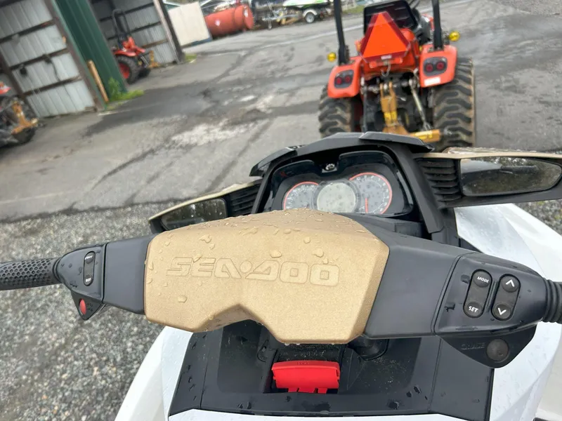 Slide: The Image of 2012 Sea-Doo GTX 155 dashboard with controls, parked near a red tractor. - 23