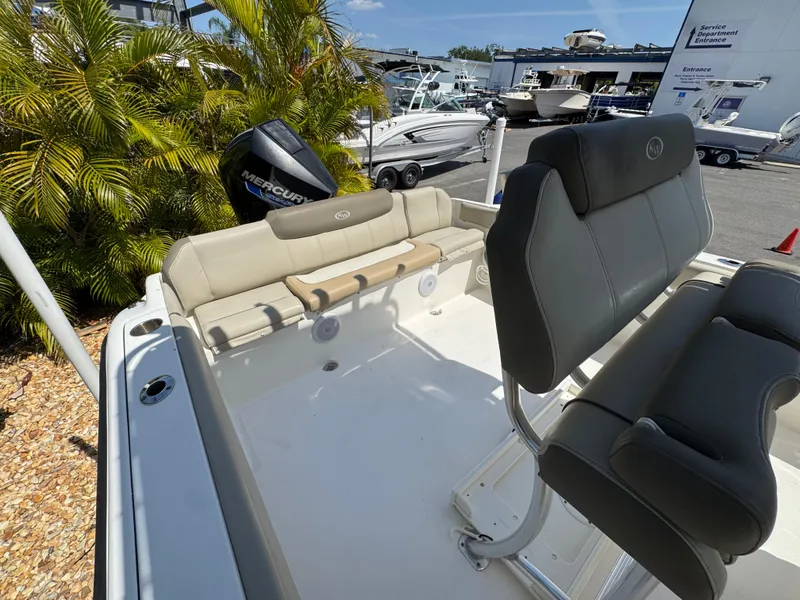 Slide: The Image of 2022 Key West 239 FS boat interior with seating and Mercury engine, docked near palm trees. - 29
