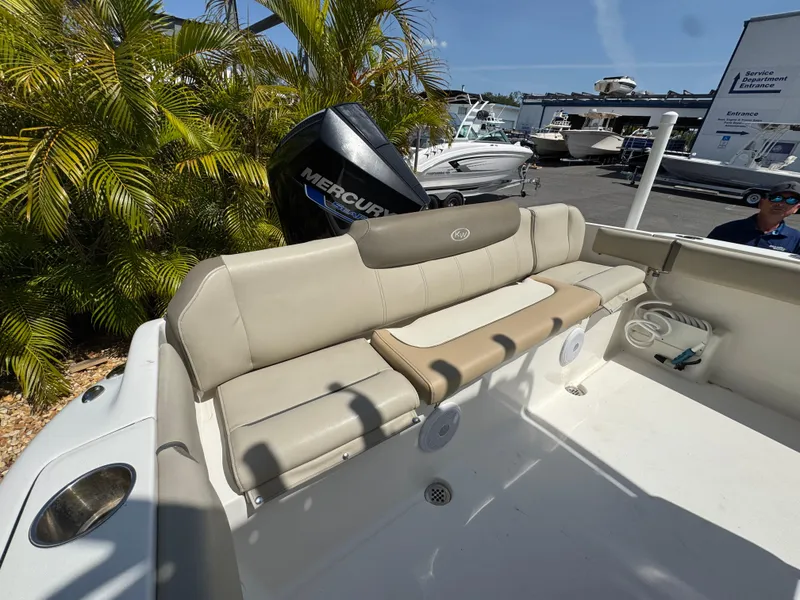 Slide: The Image of 2022 Key West 239 FS boat with beige seating and Mercury engine, surrounded by palm trees. - 30