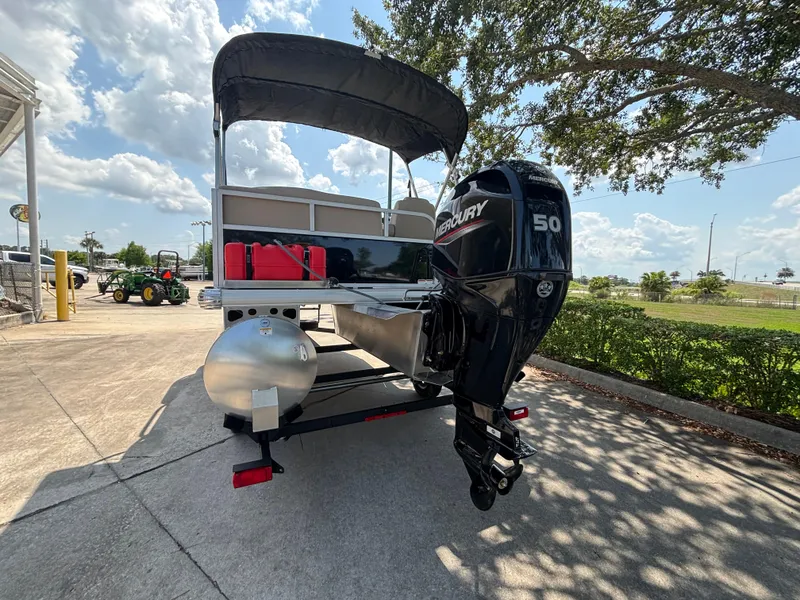 Slide: The Image of 2025 Sun Tracker Party Barge 16 DLX pontoon boat with Mercury 50 engine, parked outdoors. - 2