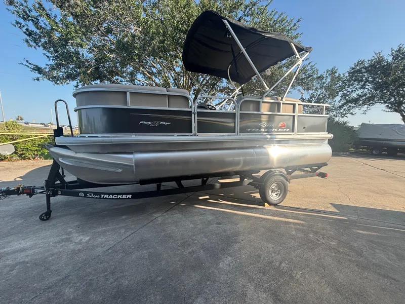 The Image of 2025 Sun Tracker Party Barge 18 DLX pontoon boat on trailer, parked outdoors. - 0