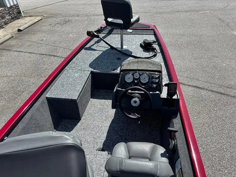 Slide: The Image of 2025 Tracker Pro 170 boat interior with steering console and seating, parked on pavement. - 9