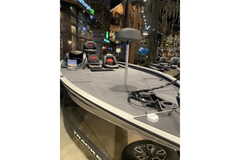 The Image of 2025 Tracker Savage 215 boat displayed indoors with modern seating and steering. - 0