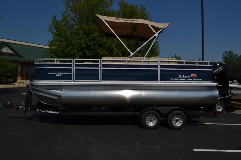 The Image of 2025 Sun Tracker Fishin' Barge 20 DLX pontoon boat with canopy on trailer. - 0