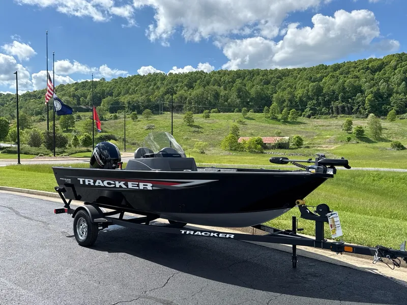 Slide: The Image of 2025 Tracker Pro Guide V-16 SC boat on trailer, scenic background, flags, and blue sky. - 2